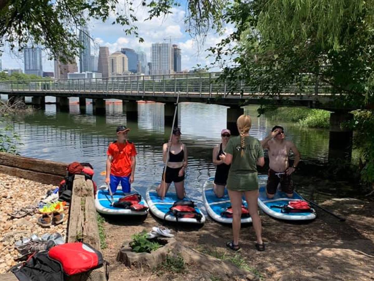 a group of people sitting on a bench next to a river
